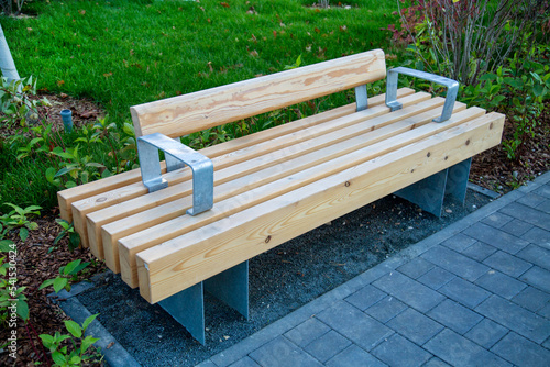 A bench made of wooden bars on yellow metal supports in the courtyard of the house outdoors. Sports healthy lifestyle Hobby.
