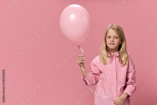 horizontal portrait of a girl in a pink shirt on a pink background with a pink balloon in her hand