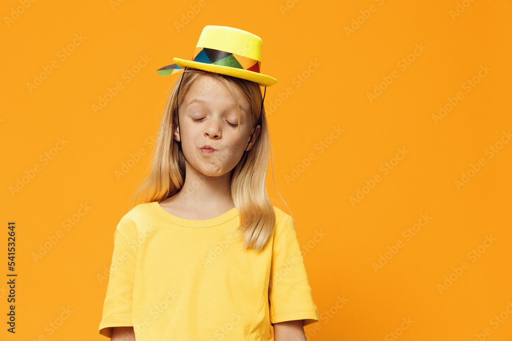 a cute, funny girl, of school age, stands on a yellow background in a yellow T-shirt in a straw hat. Horizontal studio photography with blank space for advertising mockup a cute, funny girl, of school age, stands on a yellow background in a yellow T-shirt in a straw hat. Horizontal studio photography with blank space for advertising mockup
