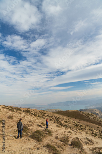 Dagestan, Russia - October 2020: Tourists walking on the mountain in the background of cloudy sky. The Chirkeyskoye reservoir is the largest artificial reservoir in the Caucasus. on the Sulak River. © Анастасия Смирнова