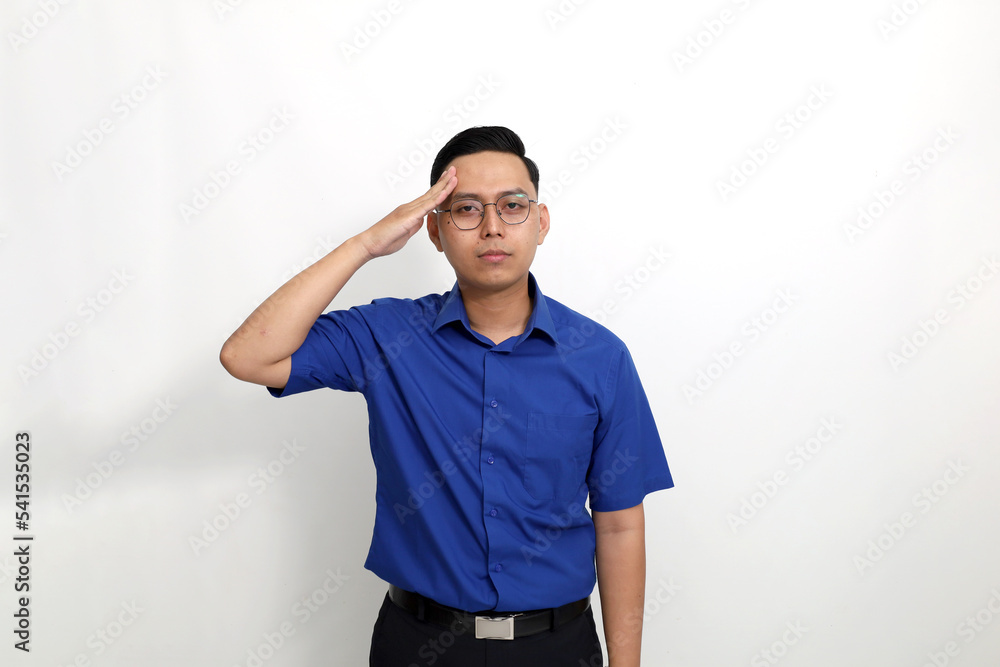 Fototapeta premium Young asian man standing with salute hand gesture and looking at the camera. Isolated on white