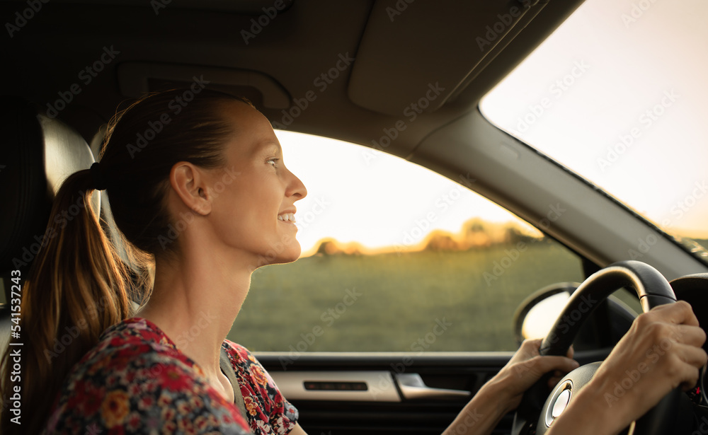 Happy young attractive female driving her car early morning 