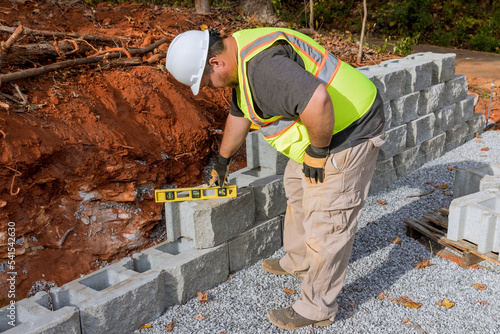 Contractor during installation of new large block retaining wall in construction site