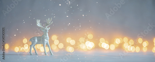 Shallow depth of field image of a Christmas deer figurine in a snowy landscape with bokeh lights