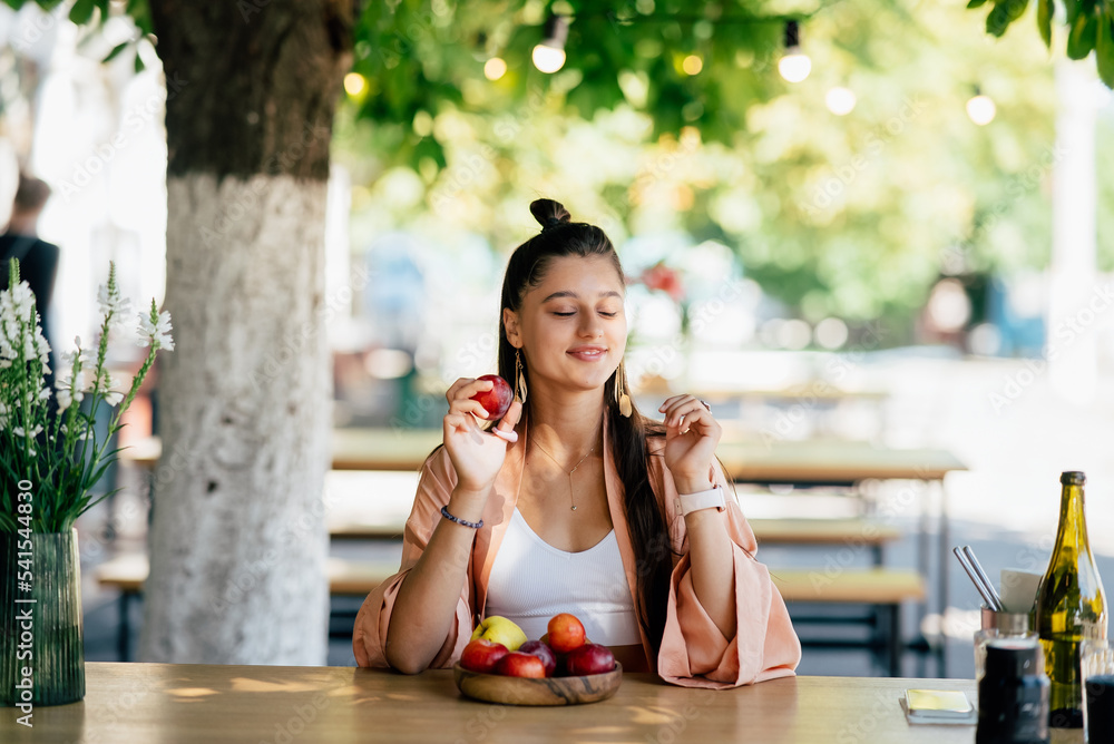 Young beautiful hipster woman sitting in veranda cafe in street.