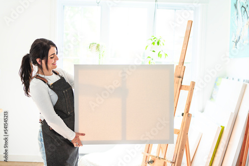 Portrait of a woman artist with canvas projects on her studio