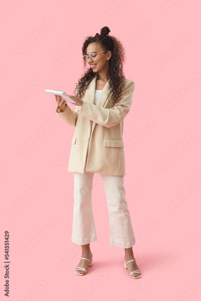 Young African-American woman with computer keyboard on pink background Young African-American woman with computer keyboard on pink background
