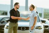 Shot of a men buying car to a car seller outside of the garage