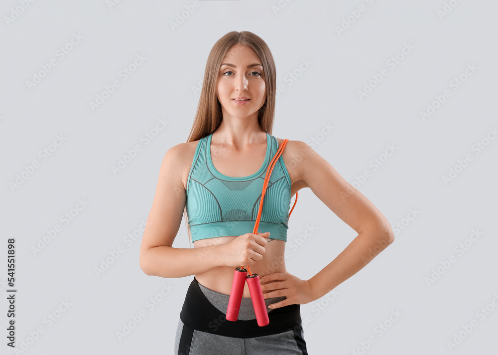 Sporty young woman with jumping rope on light background Sporty young woman with jumping rope on light background