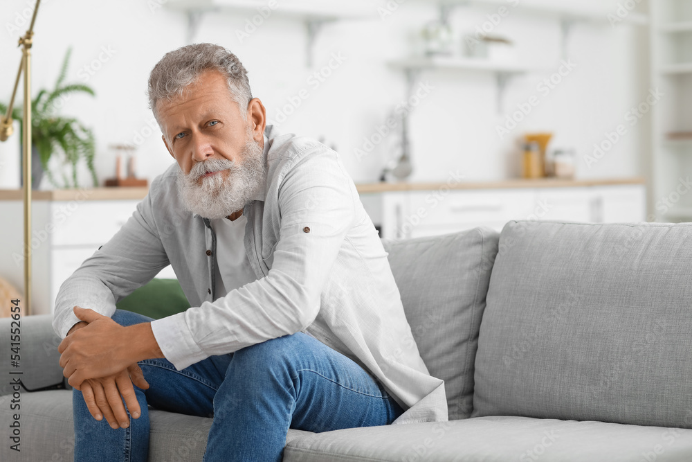 Senior bearded man sitting on sofa in kitchen