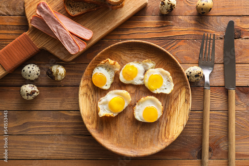 Plate with tasty fried quail eggs on wooden table