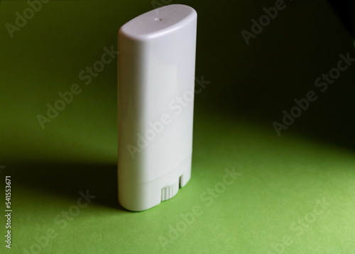 White plastic packaging used to store dermo cosmetics and for application mainly to the skin of the face. On a green background and highlighting the packaging impulse mechanism.