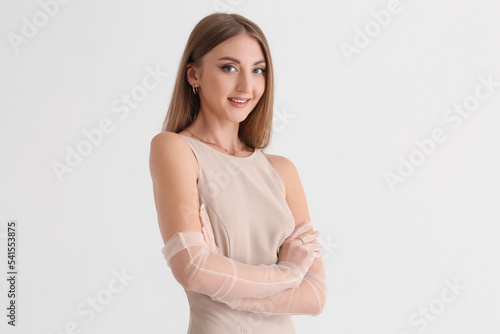 Beautiful fashionable young woman in elegant beige dress on white background