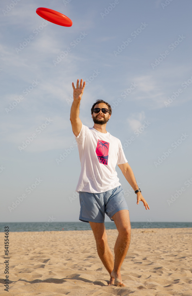 The man in motion catches a Frisbee. Frisbee game. Beach activities. A time for rest. Summer entertainment
