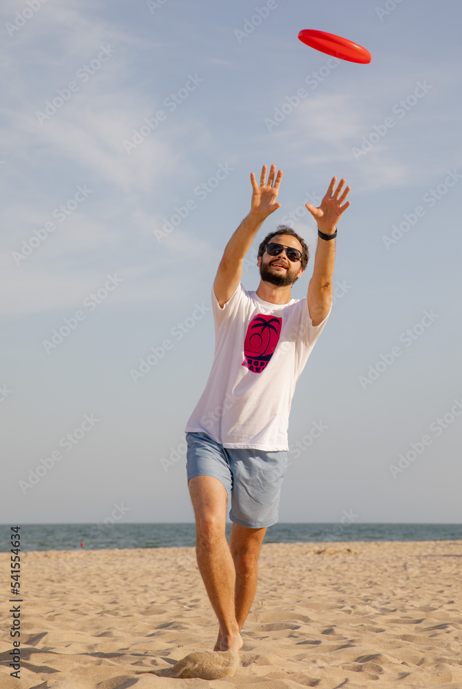The man in motion catches a Frisbee. Frisbee game. Beach activities. A time for rest. Summer entertainment
