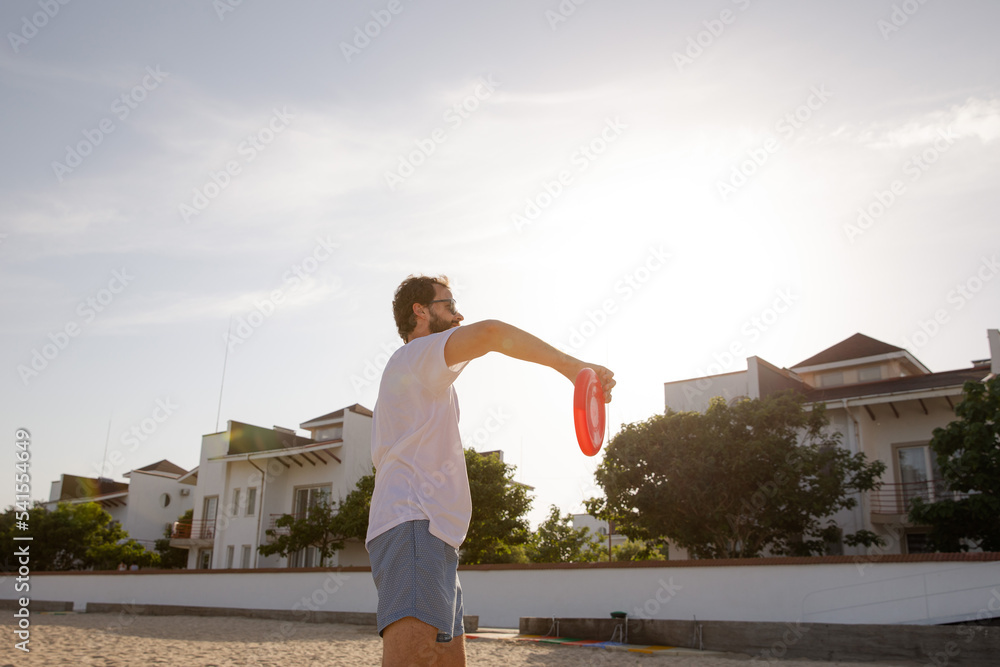 The man in motion catches a Frisbee. Frisbee game. Beach activities. A time for rest. Summer entertainment