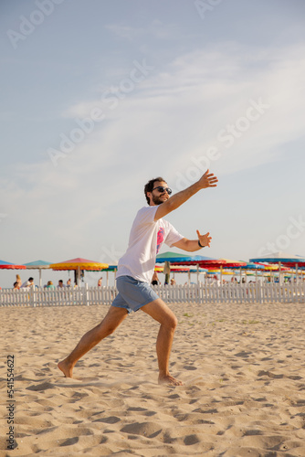The man on the beach catches a Frisbee. Frisbee game. Beach activities. Time for relaxation. Summer entertainment