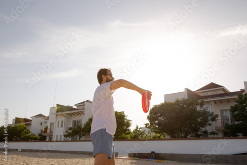 Obraz na płótnie The man in motion catches a Frisbee. Frisbee game. Beach activities. A time for rest. Summer entertainment w salonie