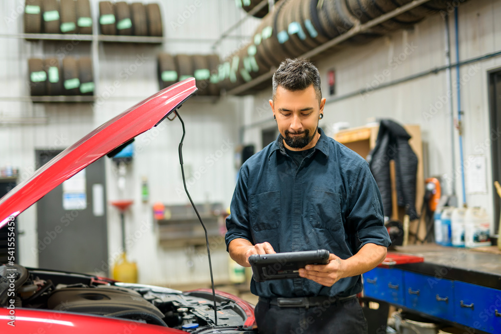 Handsome mechanic job in uniform working on car Handsome mechanic job in uniform working on car