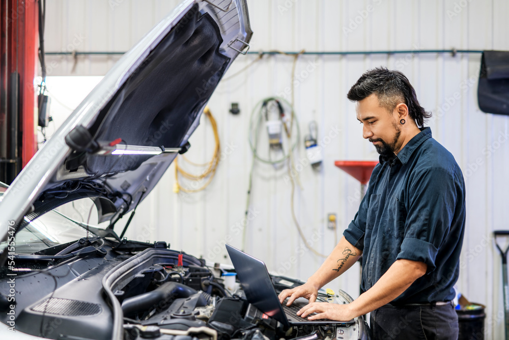 Handsome mechanic job in uniform working on car Handsome mechanic job in uniform working on car