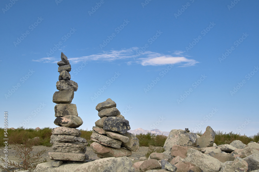 Two rock cairns stacked on a rock with a blue sky background at the Great Salt Lake State Park in Utah.