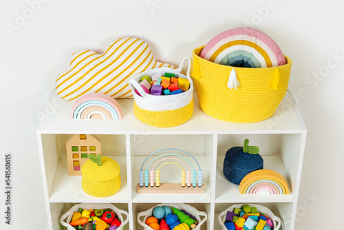 White shelving with rainbow wooden toys and colorful storage baskets. Interior design. Organizing and storage ideas in nursery.