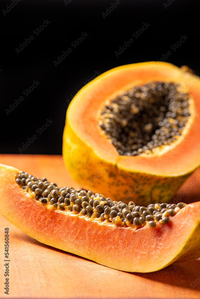Papaya, details of a sliced papaya over rustic wood, selective focus. Papaya, details of a sliced papaya over rustic wood, selective focus.