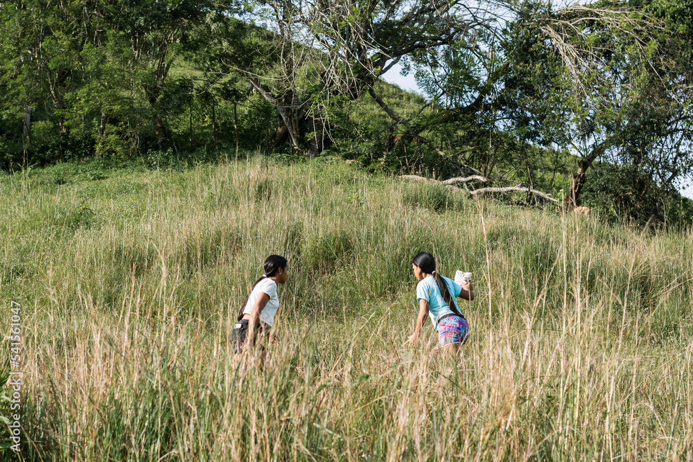 two peasant girls, brunette latinas climbing to the top of a mountain, going on an errand. women walking up the side of a Colombian mountain a long way to reach their destination.