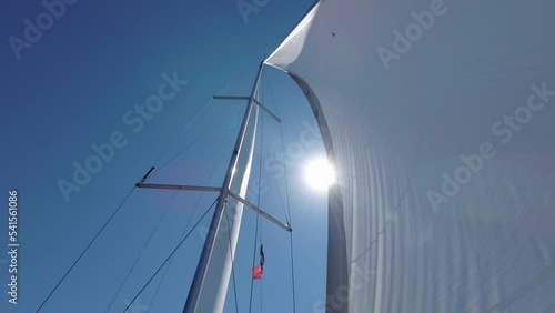 4K Sailboat Mast and Sail. Open, unfurled sails on a yacht. Sailing in the wind. Full sails, very strong wind. Lens Flare Light Leak Wind Power. Sun sails and Sunlight photo