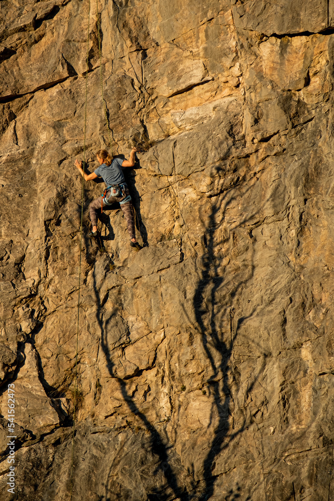 a person climber climbing a steep rock wall a person climber climbing a steep rock wall