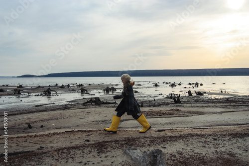 girl in big yellow rubber boots walking at seashore