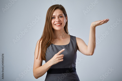 Smiling woman holding empty hand and pointing finger. Isolated female portrait
