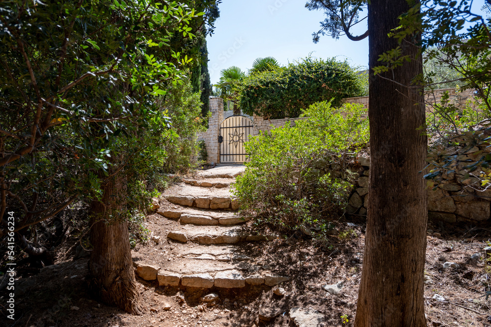 Beautiful stone fence and steel gates of mediterranean villa on the shore of Supetar on Brac island, Croatia, hidden in dense, pine trees Beautiful stone fence and steel gates of mediterranean villa on the shore of Supetar on Brac island, Croatia, hidden in dense, pine trees
