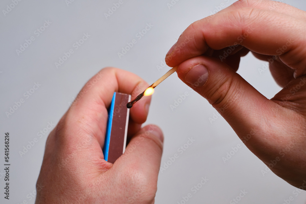A man lights a match using a matchbox. Live flame from a match close-up A man lights a match using a matchbox. Live flame from a match close-up