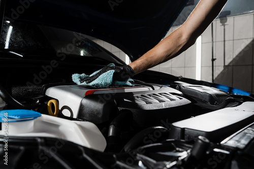 Wiping the car engine with microfiber after washing motor in car detailing service. Detailing cleaning motor from dust and dirt. © Rabizo Anatolii