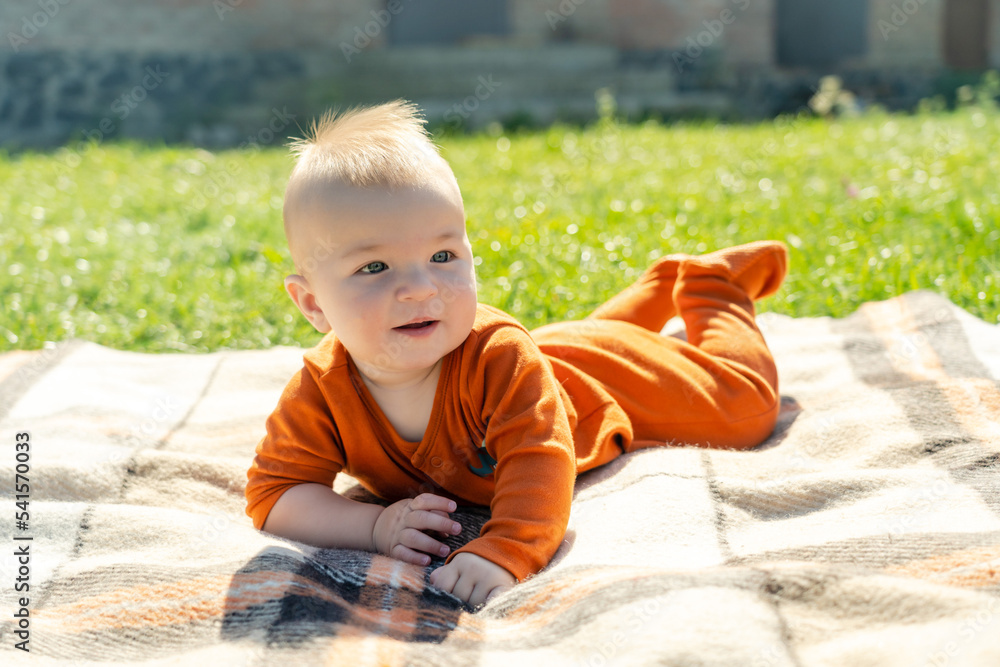 Beautiful baby lying on the plaid on sunny grass