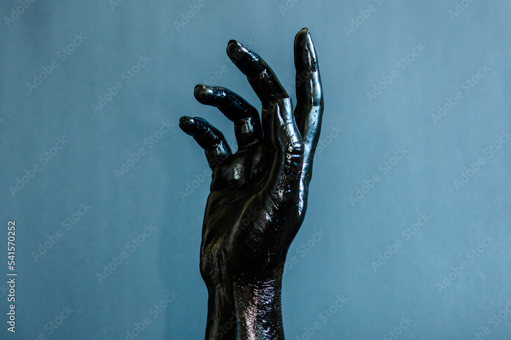 Elegant woman's hand with black paint on her skin with black background