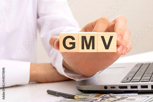 hand holds wooden cubes with inscription GMV, white background. help and tips concept photo