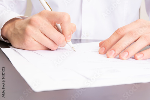 close shot of a human hand writing something on the paper on the foreground, business concept