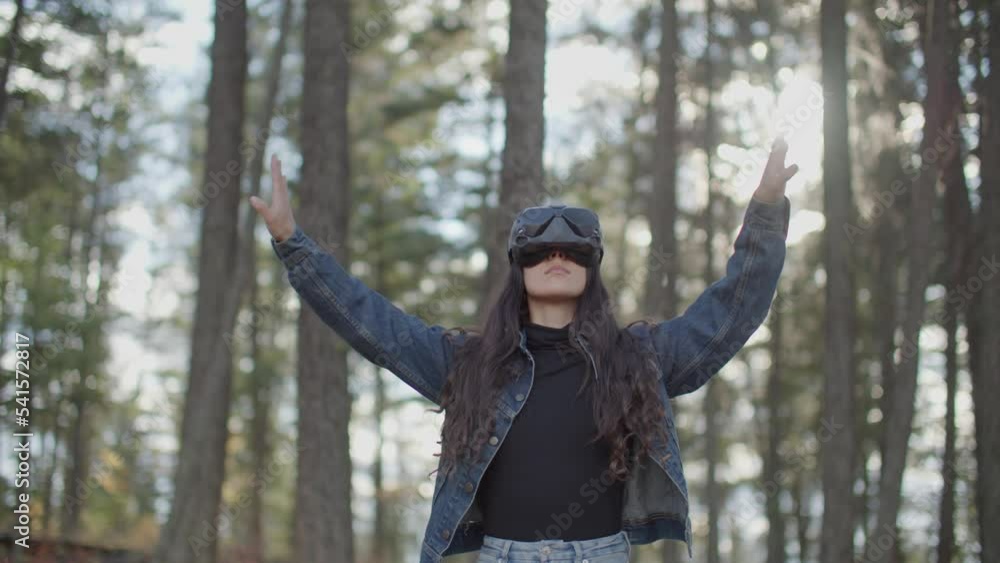Young woman wearing vr goggles using virtual reality interface in nature Young woman wearing vr goggles using virtual reality interface in nature