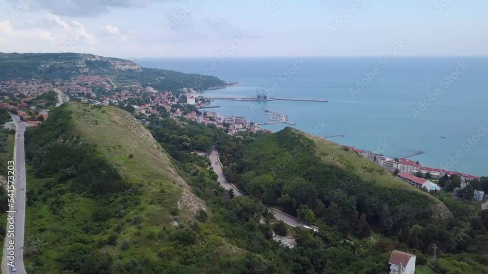 Aerial view of a rocky coastline and large village with houses on a summer day with cloudy sky. Roads with cars, hotels and trees are visible on the hilly area. Bulgaria and the Black Sea Aerial view of a rocky coastline and large village with houses on a summer day with cloudy sky. Roads with cars, hotels and trees are visible on the hilly area. Bulgaria and the Black Sea