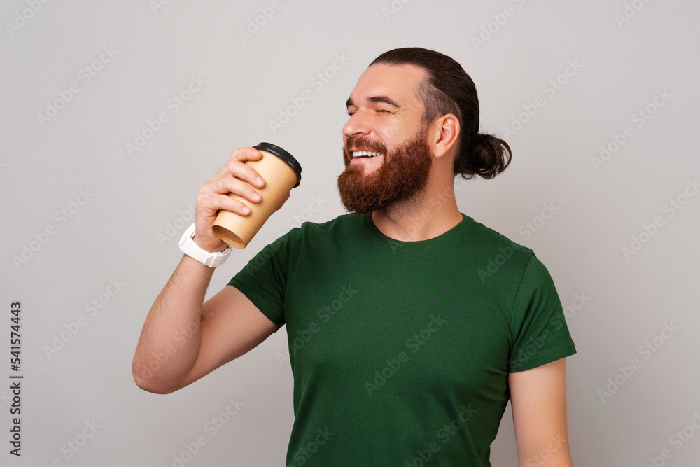 Side view photo of young handsome man with beard in green t-shirt enjoying his morning cappuccino Side view photo of young handsome man with beard in green t-shirt enjoying his morning cappuccino