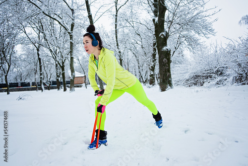 Athletic fitness woman doing exercise with resistance band on winter snowy park, forest background. Fitness woman working out With Resistance Loop Band outdoors cold season