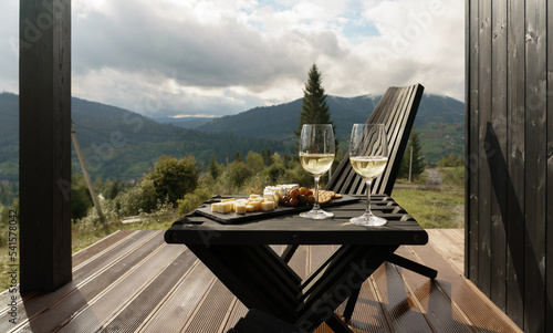 Photography White wine glasses and plate of cheese on terrace with mountains view