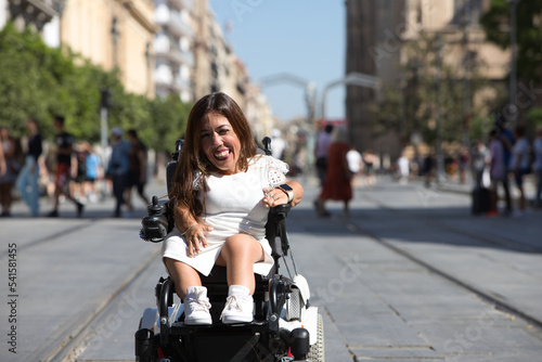 beautiful young disabled woman in wheelchair and reduced mobility enjoys her trip around the city where she is on vacation.