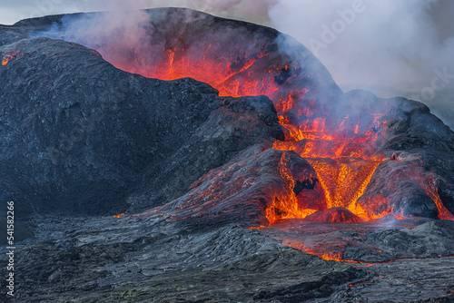 View into the crater opening from the side. Lava flow from the crater of a volcano on Iceland. Landscape on Reykjanes Peninsula in GeoPark. Heavy smoke development over the crater during the day