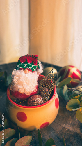 Fototapeta Naklejka Na Ścianę i Meble -  Santa Claus doll inside a Christmas cup with Christmas decorations vertical