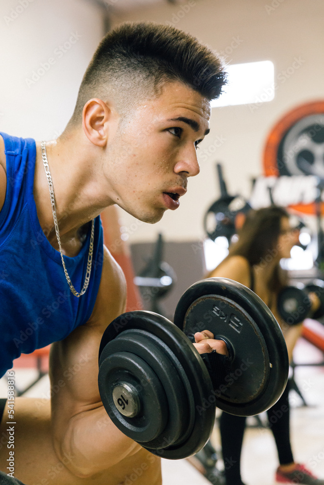 Young bodybuilder working out lifting dumbbells at the gym. Young bodybuilder working out lifting dumbbells at the gym.