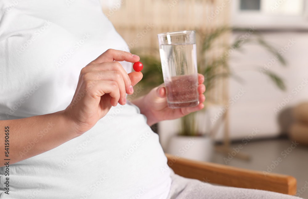 Pregnant woman taking pill at home, closeup Pregnant woman taking pill at home, closeup