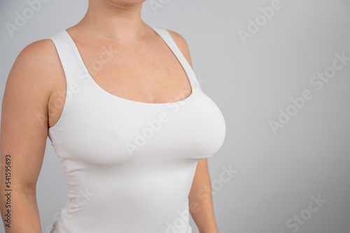 Close-up of a female breast before and after augmentation. A woman tries on a silicone implant before surgery.